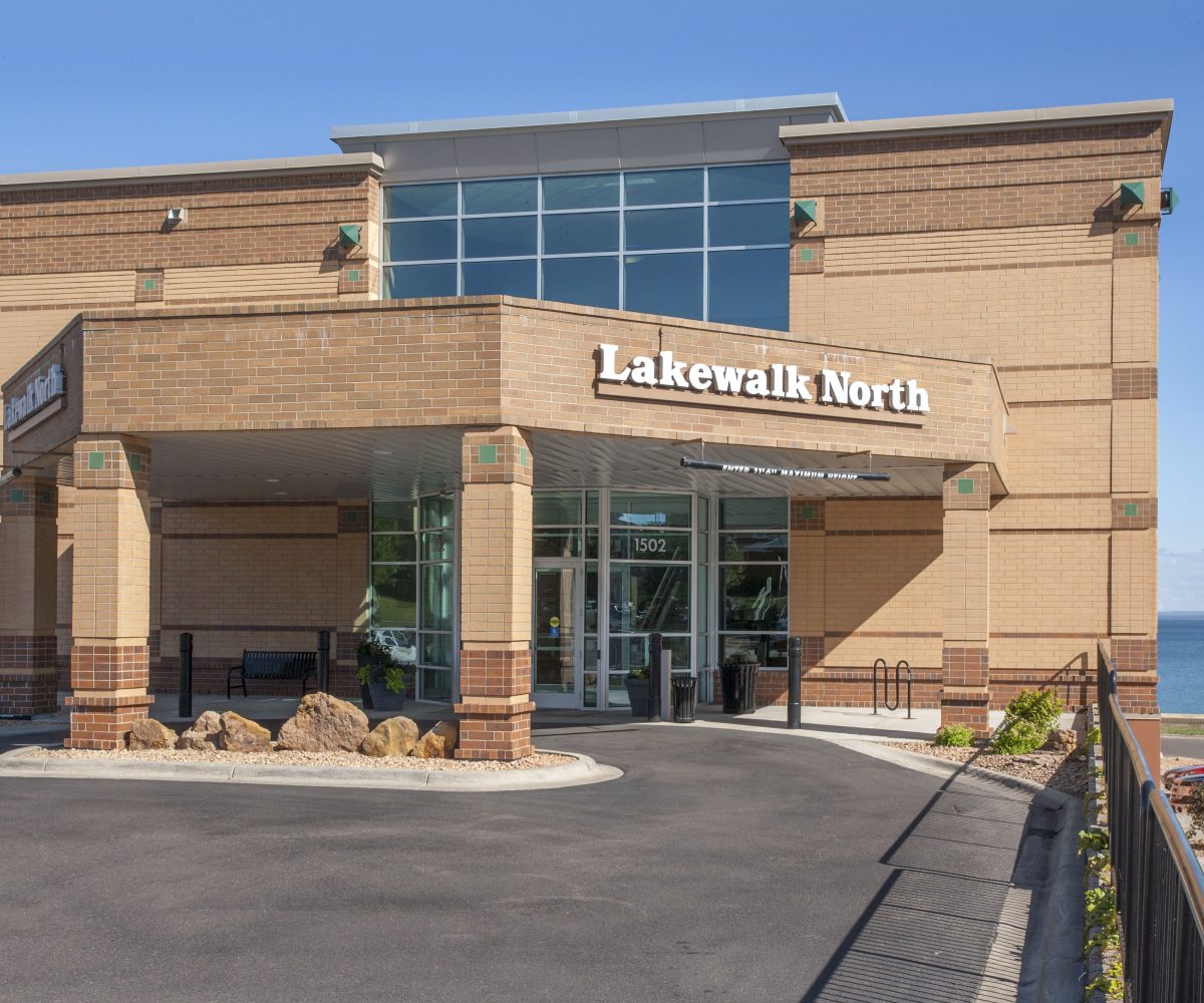 Exterior view of the entrance to the Lakewalk North building with Lake Superior in the background