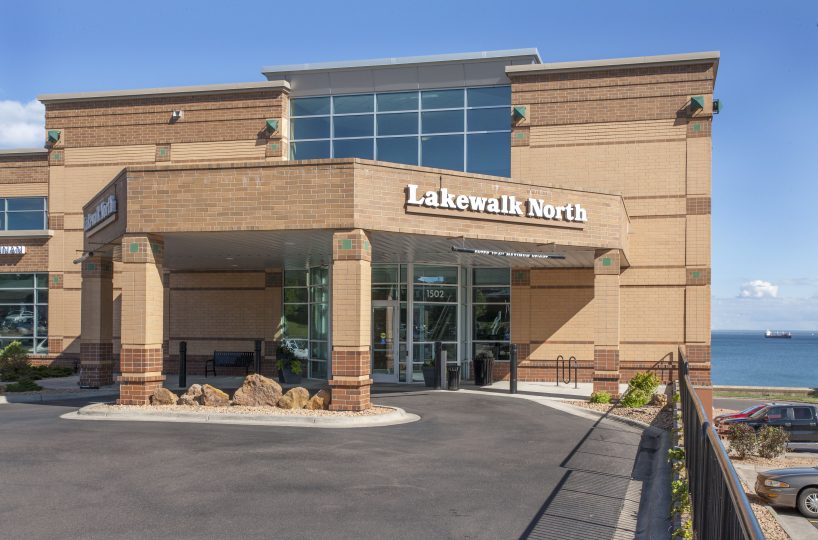 Exterior view of the entrance to the Lakewalk North building with Lake Superior in the background